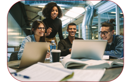 Four students in a library working together around two laptops